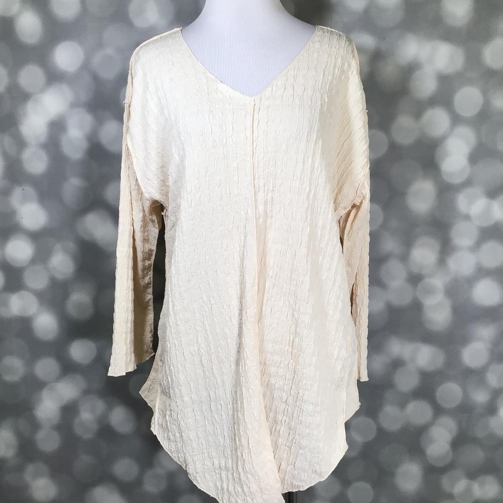 LuLaRoe Jolene V-neck tunic top in solid vanilla gauze bubble jacquard fabric displayed on a mannequin. Long sleeve, relaxed-fit tunic in a soft creamy neutral with textured finish.