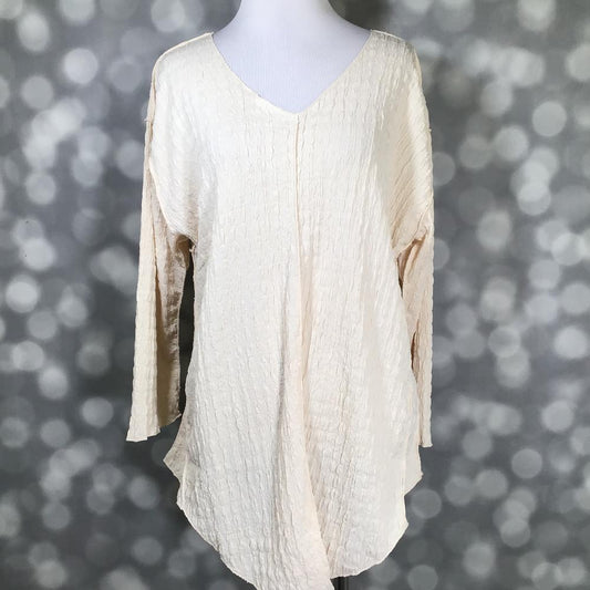 LuLaRoe Jolene V-neck tunic top in solid vanilla gauze bubble jacquard fabric displayed on a mannequin. Long sleeve, relaxed-fit tunic in a soft creamy neutral with textured finish.