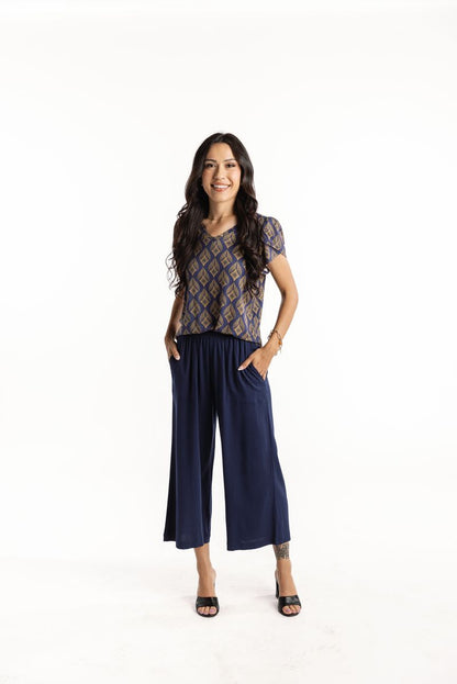 LuLaRoe Justine wide-leg pants in solid navy blue, featuring elastic waistband, relaxed cropped fit, styled with patterned blouse and heels for a polished everyday look on a white background