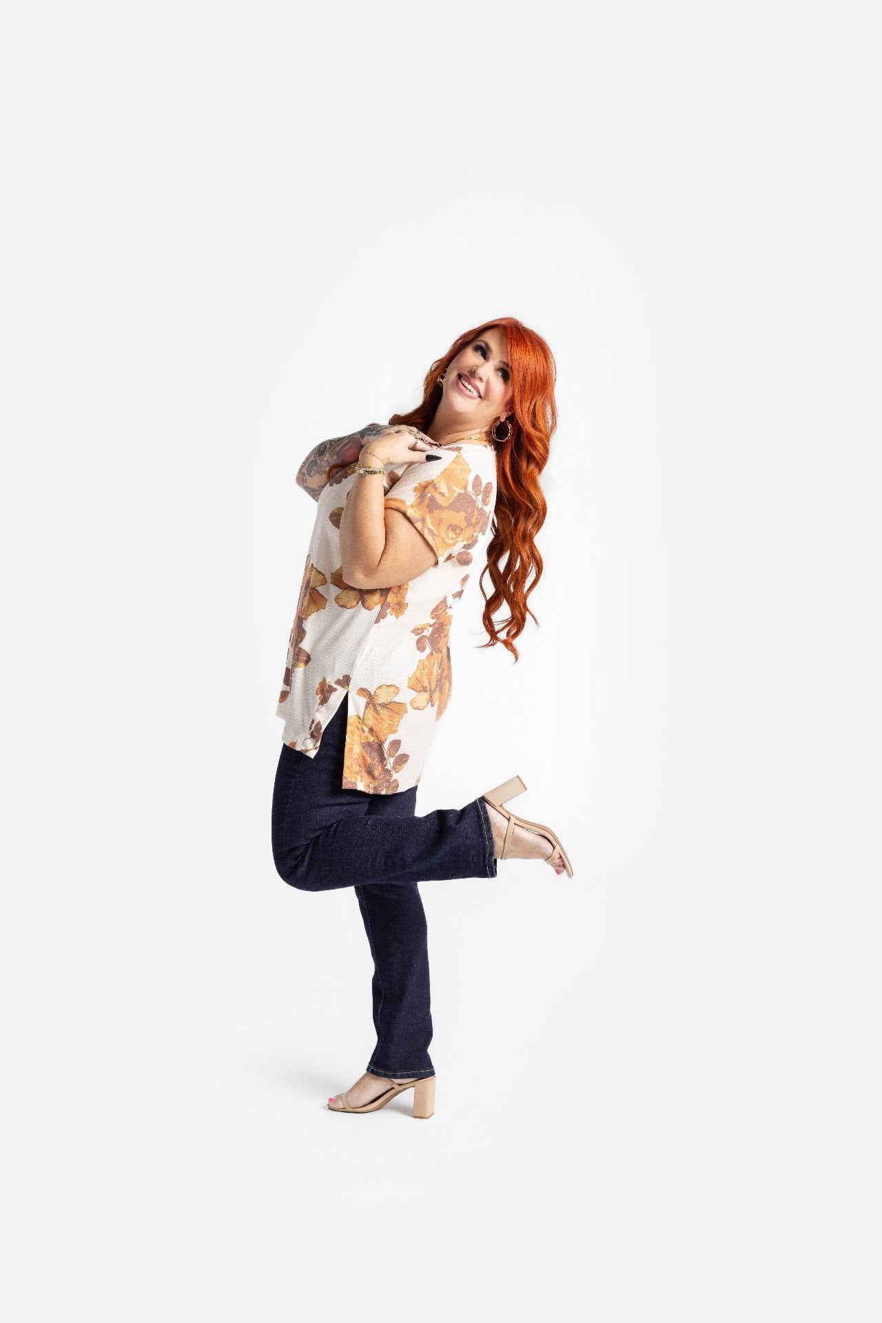 LuLaRoe Leah top in cream with golden amber floral print and brown leaf accents, relaxed fit women’s boutique fall floral top on a woman with dark pants posing on a white background