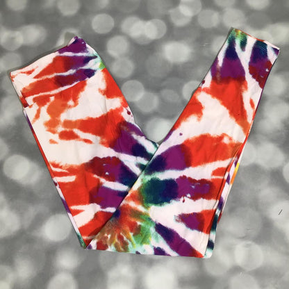 Multicolor LuLaRoe leggings featuring vibrant orange, purple, blue, green, and white abstract tie-dye watercolor patterns photographed folded flat against a silver bokeh background.