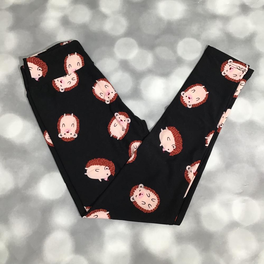 LuLaRoe leggings featuring a black background with repeating illustrated hedgehog faces in blush and brown tones arranged in a playful novelty pattern