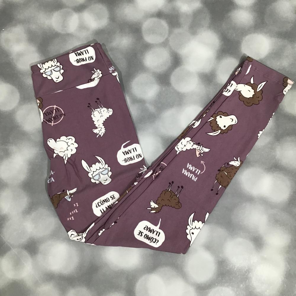 LuLaRoe leggings with a playful llama print and speech bubbles on a mauve purple background, shown in flat lay on a blurred gray background