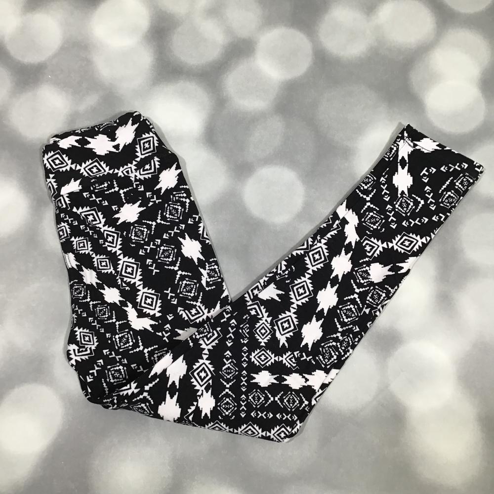 LuLaRoe leggings in Midnight Aztec with bold black-and-white geometric tribal-inspired print. on a blurred gray background