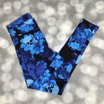 LuLaRoe leggings featuring a black background with blue floral blooms and light blue skull motifs in an all-over novelty print floral and skull pattern on a blurred background