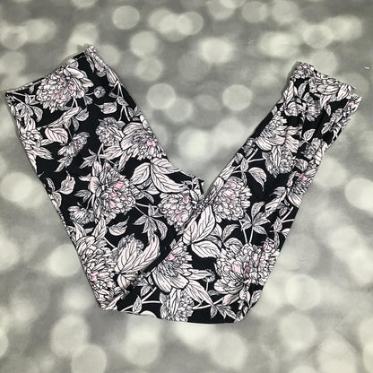 LuLaRoe leggings in black with ivory peony floral print and soft blush pink accents in a fitted stretchy silhouette on a blurred background