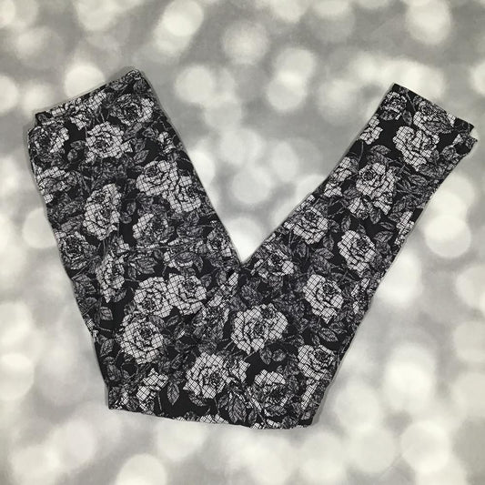 LuLaRoe leggings featuring an allover ivory rose floral print with a textured etched design on a black background, laid flat on a light gray surface.
