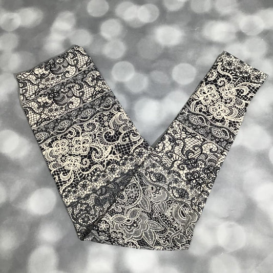 LuLaRoe leggings in Midnight Lacework with black background, ivory lace floral design, soft stretchy fabric, and all-over ornate pattern on a blurred background