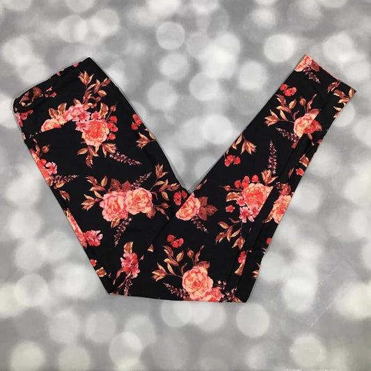 LuLaRoe leggings laid flat with a black background featuring coral and blush rose florals with leafy accents