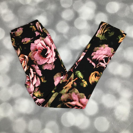 LuLaRoe leggings laid flat with a black background featuring large pink and blush rose florals with soft green leaves in a bold romantic floral pattern.