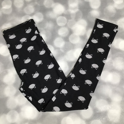LuLaRoe leggings featuring a black background with small white cat face icons arranged in a repeating minimalist pattern on a blurred light gray background