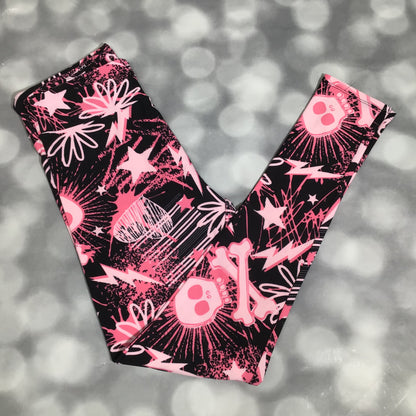 LuLaRoe leggings featuring a black background with neon pink skulls, bones, lightning bolts, and star graphics in an all-over edgy novelty print on a gray blurred background