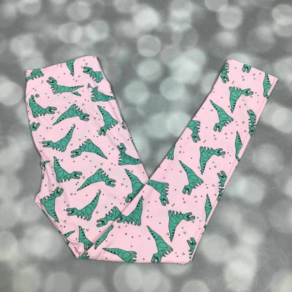 LuLaRoe leggings laid flat with a pink background and green illustrated dinosaur pattern throughout