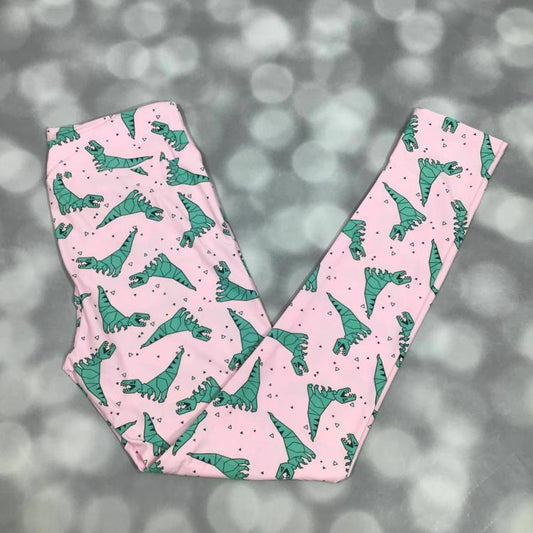 LuLaRoe leggings laid flat with a pink background and green illustrated dinosaur pattern throughout