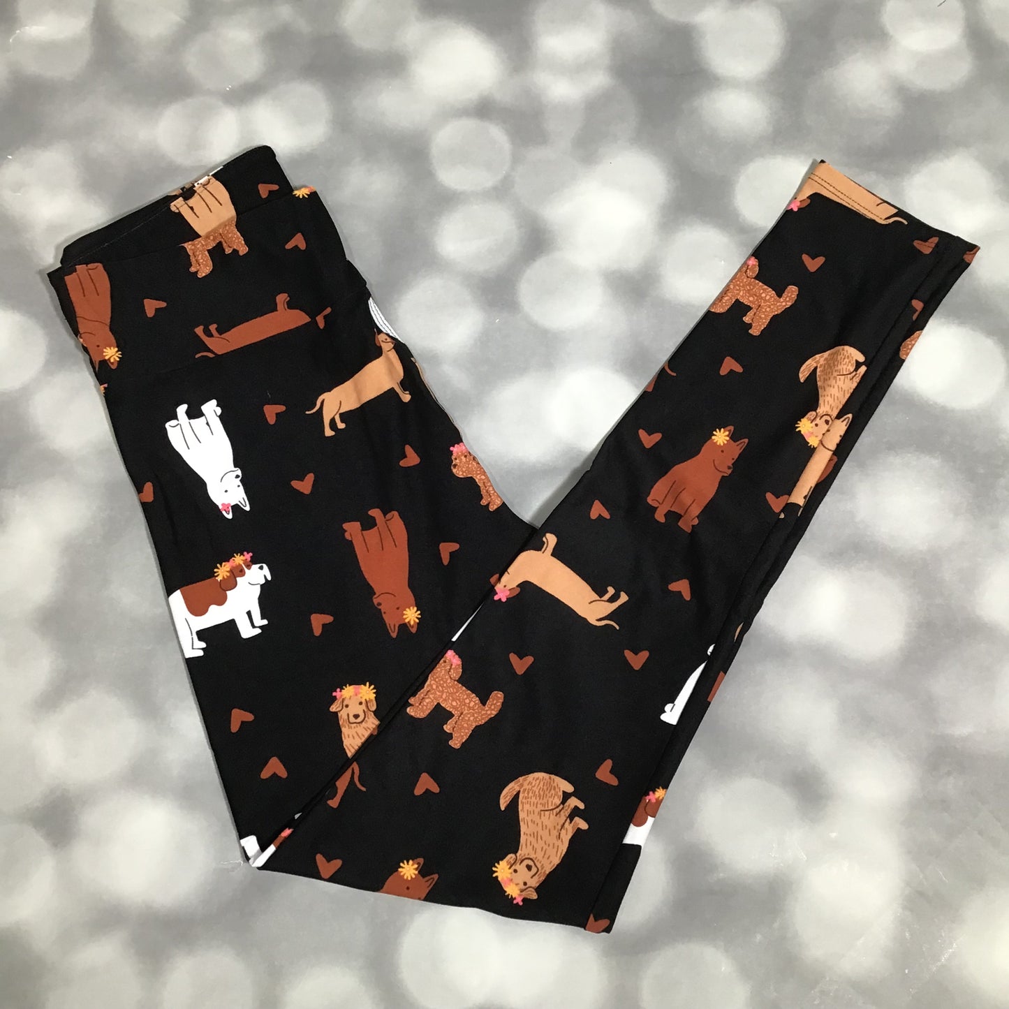 LuLaRoe leggings featuring a black background with illustrated dogs in neutral tones and small heart accents arranged in an all-over novelty pattern on a gray background
