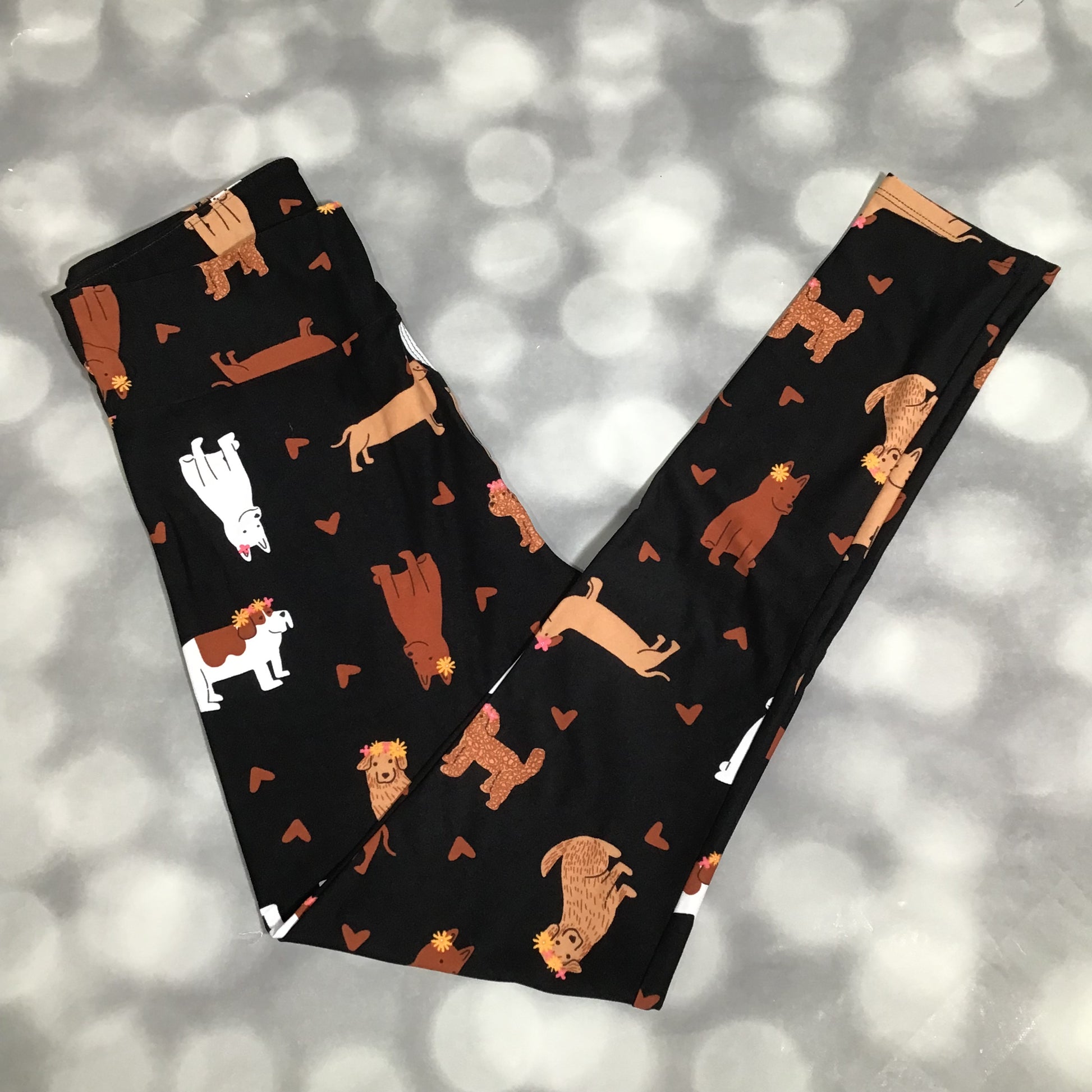 LuLaRoe leggings featuring a black background with illustrated dogs in neutral tones and small heart accents arranged in an all-over novelty pattern on a gray background