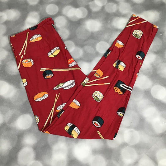 LuLaRoe leggings in a red sushi print displayed flat on a soft gray bokeh background. Features colorful sushi rolls, nigiri, chopsticks, and playful food graphics on a vibrant red base.