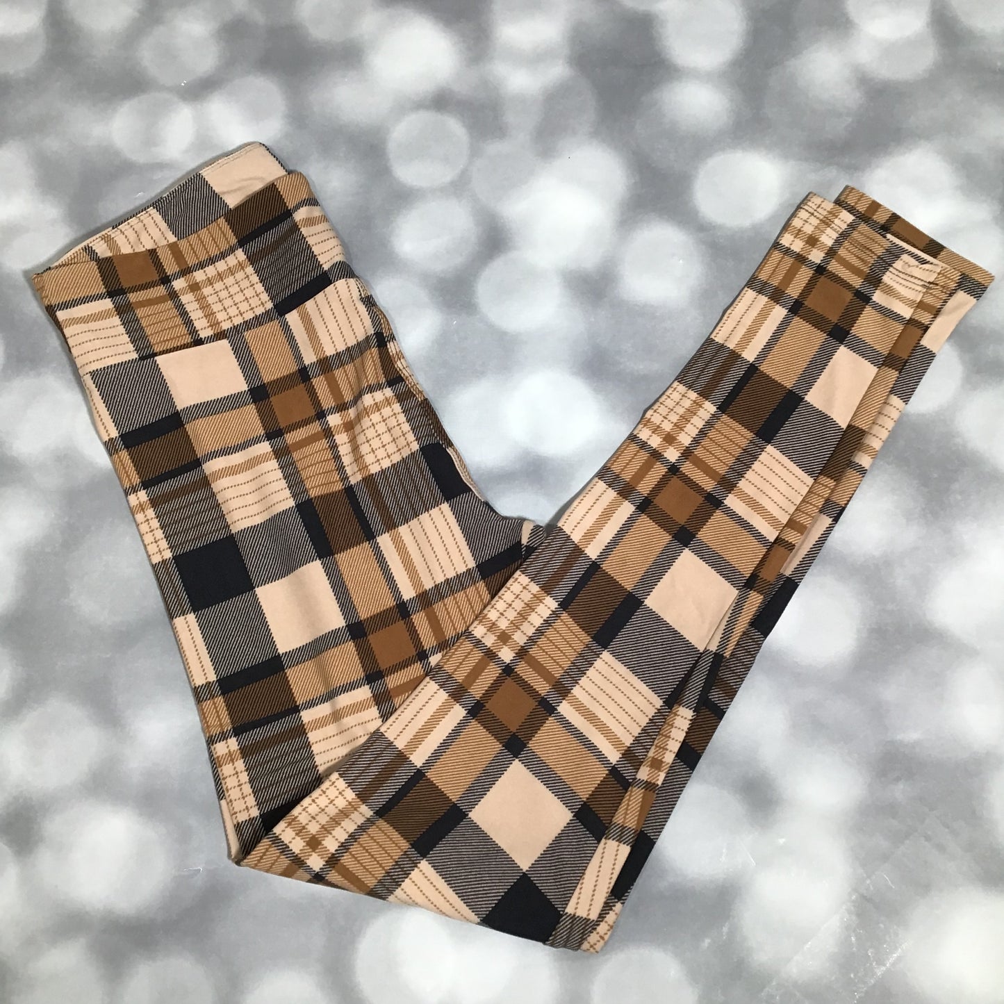 LuLaRoe leggings featuring a beige and camel plaid pattern with tan and black checks in a soft, cozy all-over design on a gray background