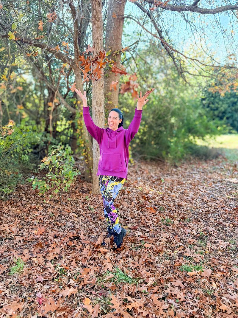 Lexi Hooded Fleece Sweatshirt in solid berry purple shown on a model outdoors. Relaxed-fit hoodie with raglan sleeves, kangaroo pocket, ribbed cuffs and hem, and side slits.