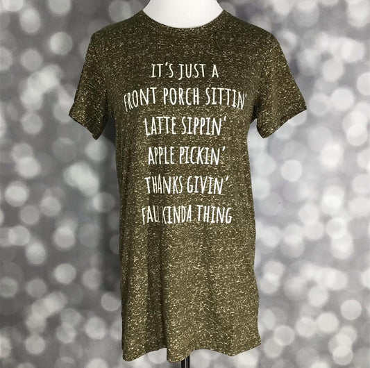LuLaRoe Liv T in heathered olive with white fall-themed text graphic” | “Front view of LuLaRoe Liv T on mannequin featuring heathered olive knit fabric and white text that reads ‘It’s just a front porch sittin’, latte sippin’, apple pickin’, thanks givin’, fall kinda thing' on a blurred background