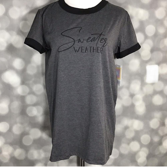 LuLaRoe Liv T in charcoal gray with black contrast trim and ‘Sweater Weather’ text graphic” | “Front view of LuLaRoe Liv T on mannequin featuring dark heather gray fabric, black neckline and sleeve trim, and minimalist ‘Sweater Weather’ lettering.