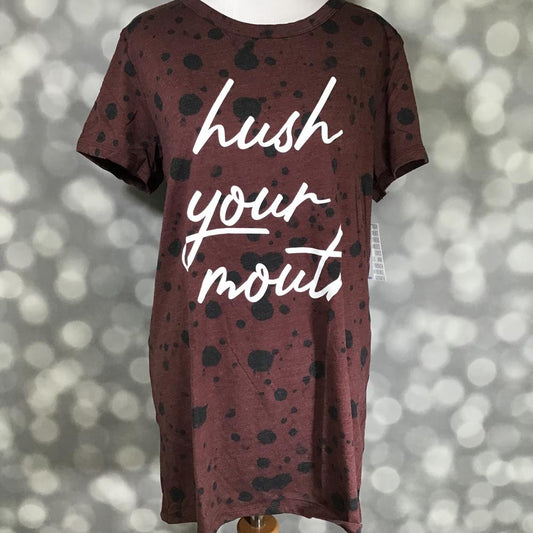 LuLaRoe Liv tee on mannequin featuring a burgundy heather background with black splatter detail and white “hush your mouth” script graphic on the front.