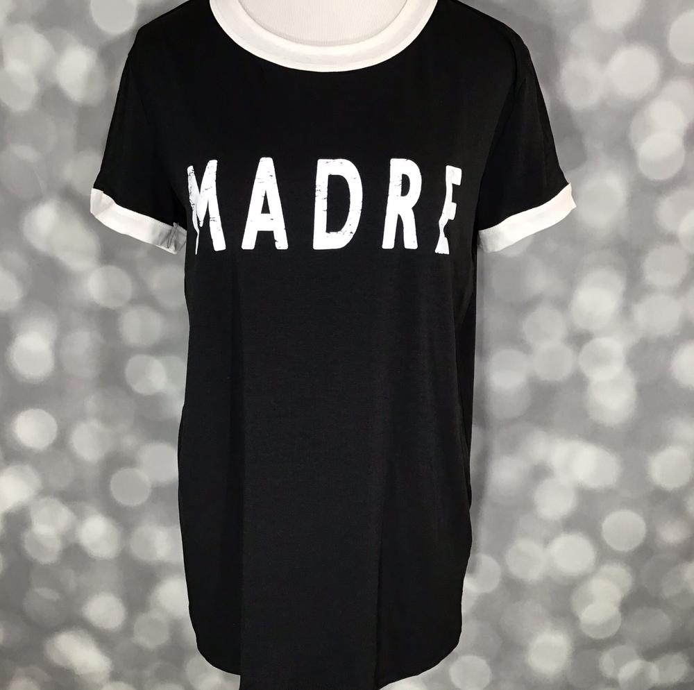 LuLaRoe Liv Tee in black with bold white “MADRE” graphic and contrast white trim at neckline and sleeves.
a blurred gray background