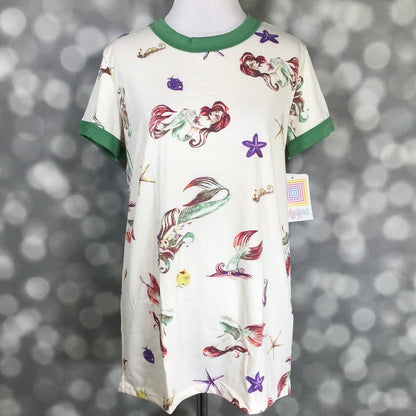 LuLaRoe Liv Tee featuring a whimsical mermaid and ocean reef print with starfish, seahorses, and sea creatures on an ivory background with green trim sleeves and neckline on a mannequin against a blurred gray background