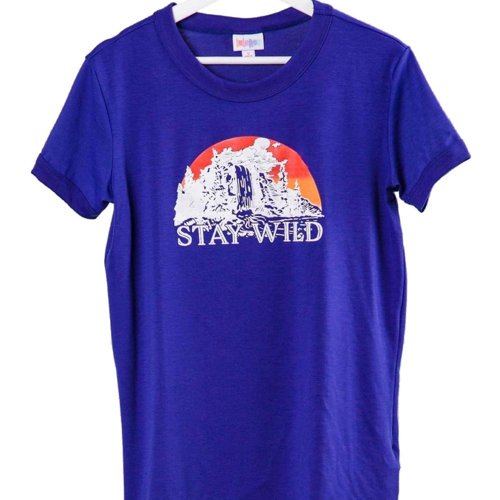 LuLaRoe Liv Tee blue shirt with 'Stay Wild' desert sunset cactus graphic design on a white background