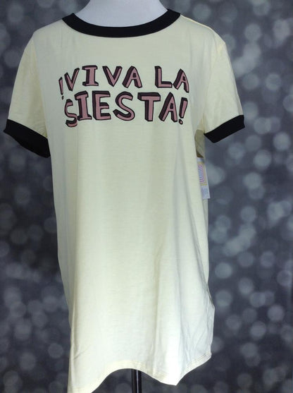 LuLaRoe Liv Tee in pale yellow with black trim and “Viva La Siesta” graphic text, featuring short sleeves, relaxed fit, and curved hem displayed on a mannequin on a blurred background