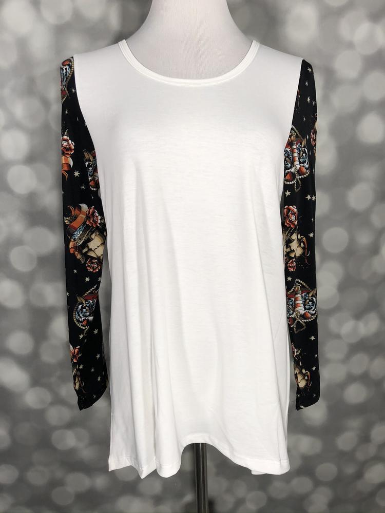 White top with black floral sleeves featuring skull and rose print on a mannequin against a blurred gray background