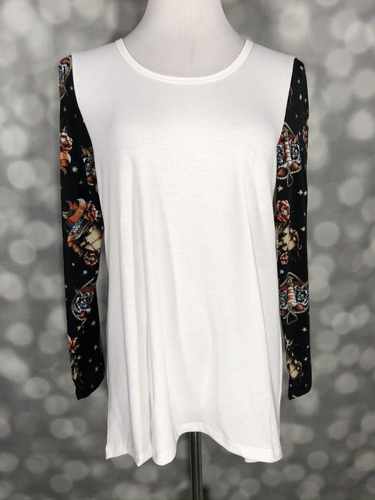White top with black floral sleeves featuring skull and rose print on a mannequin against a blurred gray background
