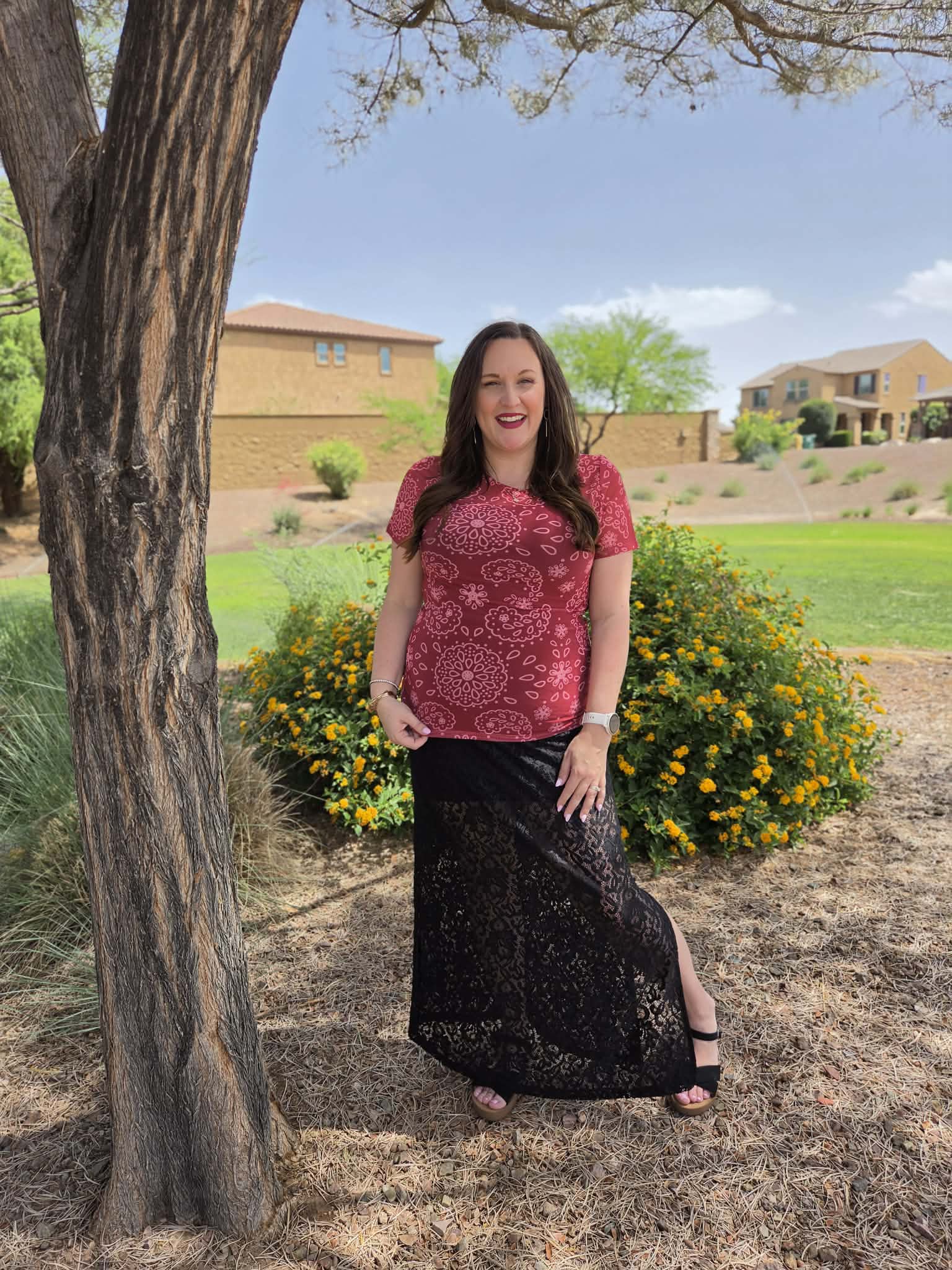 Woman wearing a deep rustic red LuLaRoe Miranda Mesh T featuring tonal paisley floral medallion prints paired with a black lace maxi skirt outdoors in a casual chic boutique fashion setting.