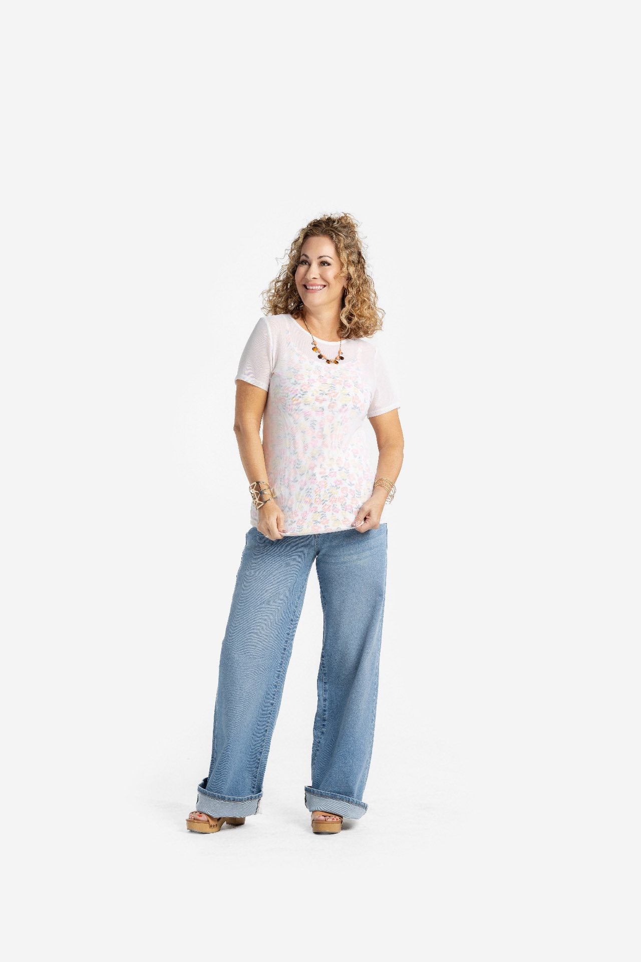 Woman wearing a solid white LuLaRoe Miranda Mesh T semi-sheer layering top with wide leg denim jeans, featuring lightweight mesh fabric, short sleeves, and an elevated casual boutique fashion look on a light studio background.