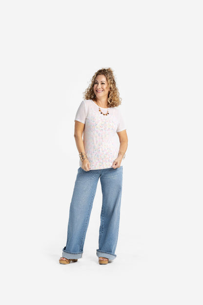 Woman wearing a solid white LuLaRoe Miranda Mesh T semi-sheer layering top with wide leg denim jeans, featuring lightweight mesh fabric, short sleeves, and an elevated casual boutique fashion look on a light studio background.