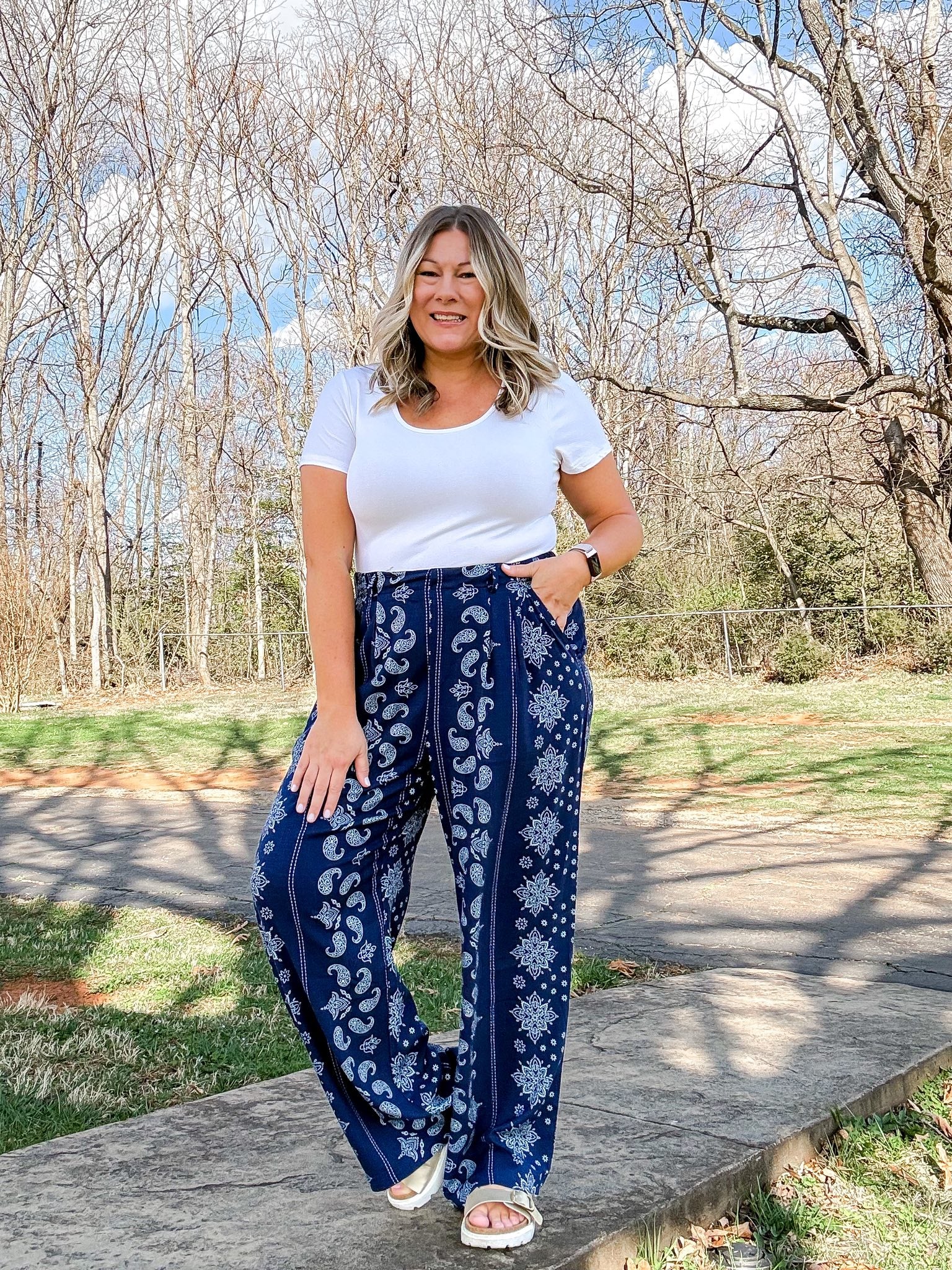 LuLaRoe Pamela Trouser in navy blue with white paisley and floral vertical panel print, styled outdoors with white top