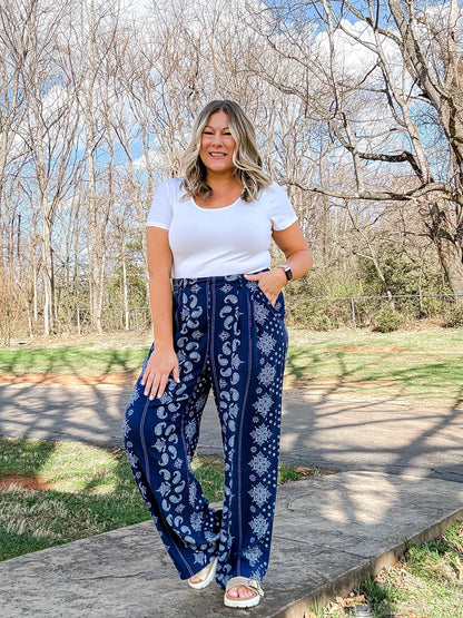 LuLaRoe Pamela Trouser in navy blue with white paisley and floral vertical panel print, styled outdoors with white top