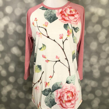 LuLaRoe Randy Tee with blush pink sleeves and cream floral rose print on a blurred background