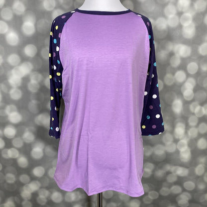 LuLaRoe Randy Tee with lavender body and navy polka dot raglan sleeves on a mannequin against a gray background