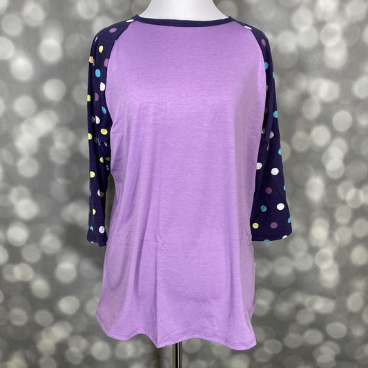 LuLaRoe Randy Tee with lavender body and navy polka dot raglan sleeves on a mannequin against a gray background