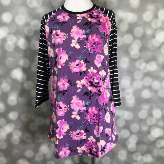 LuLaRoe Randy Tee with purple floral body and black striped raglan sleeves on a mannequin against a blurred background