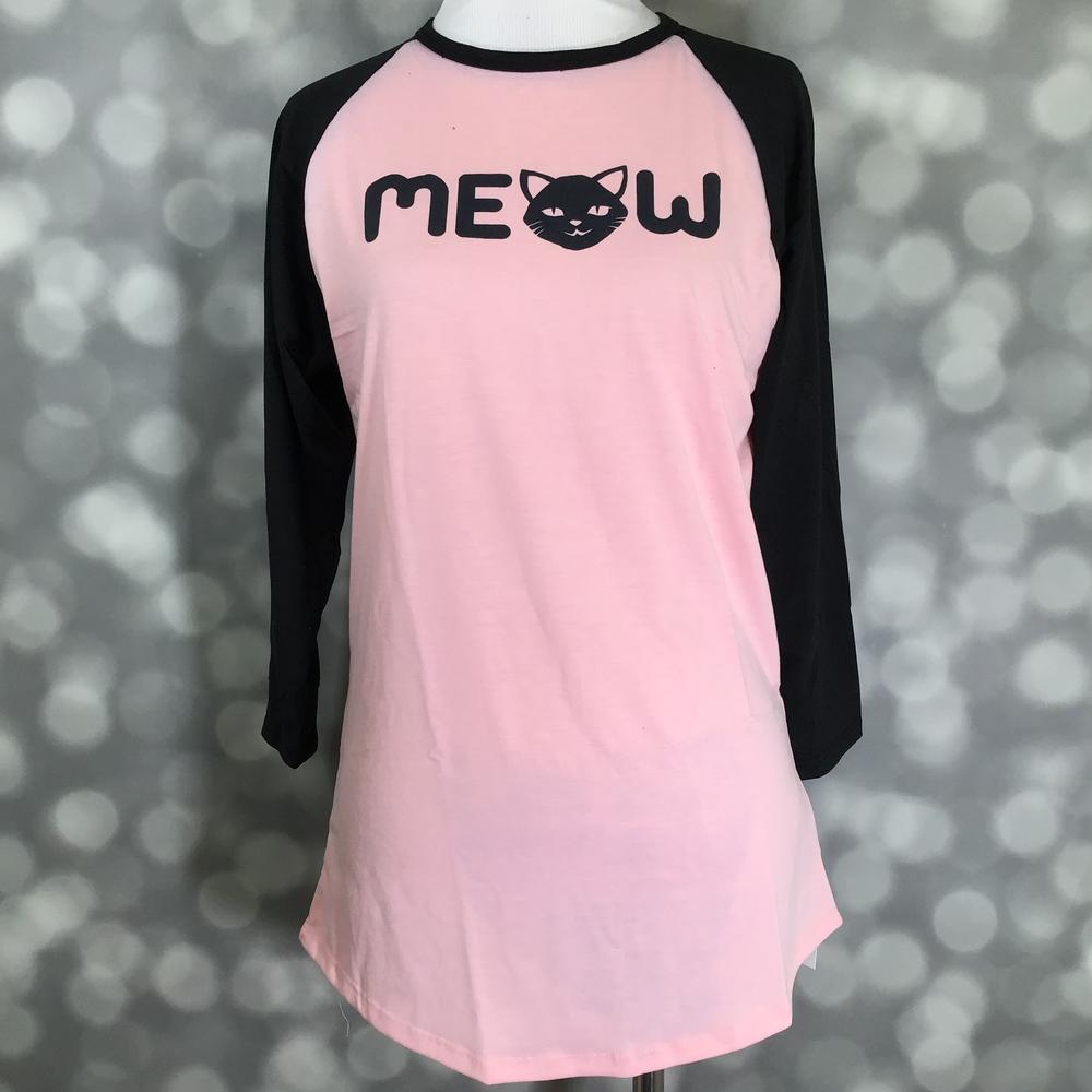 LuLaRoe Randy Tee with pink body, black raglan sleeves, and MEOW cat graphic on a mannequin against a blurred background