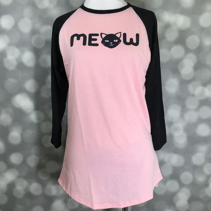 LuLaRoe Randy Tee with pink body, black raglan sleeves, and MEOW cat graphic on a mannequin against a blurred background
