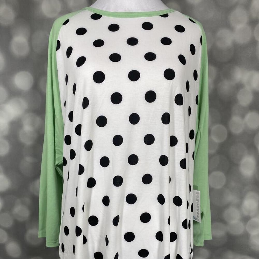 LuLaRoe Randy Tee with mint green sleeves and black polka dots on cream body on a mannequin against a blurred background
