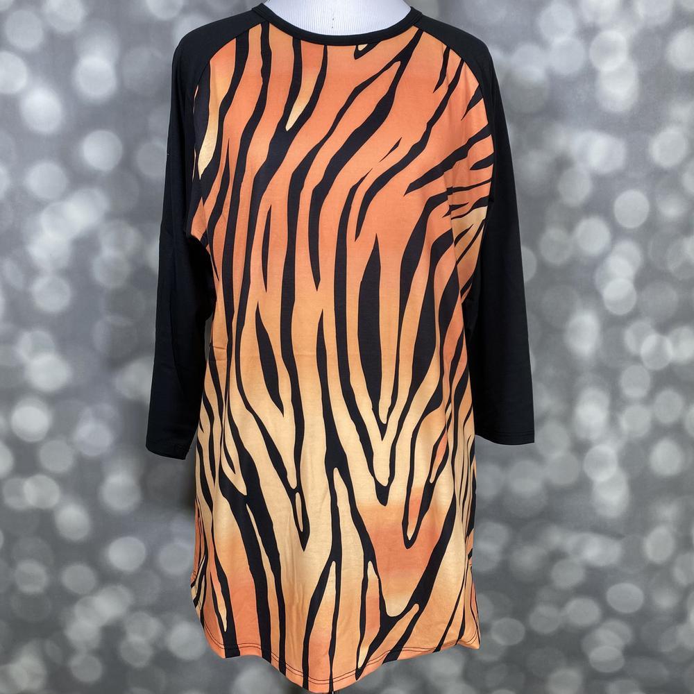 LuLaRoe Randy Tee with orange sunset tiger stripe print and black raglan sleeves on a mannequin against a blurred background