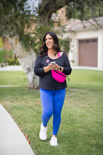 Woman wearing LuLaRoe Rise Brave leggings in solid bright blue styled with black top and pink crossbody bag walking outdoors