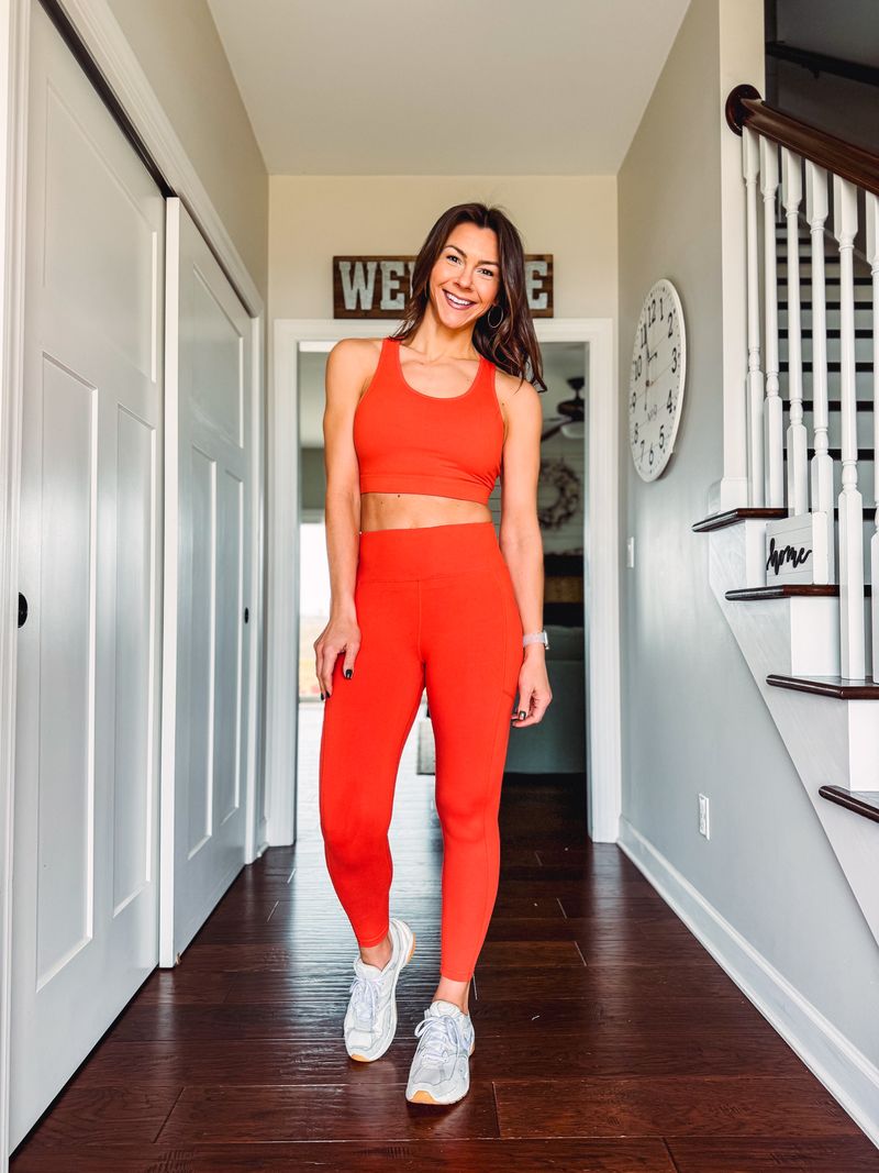 Woman in LuLaRoe Rise Brave leggings solid grenadine red athletic leggings with high waist and side pockets standing in a home hallway.