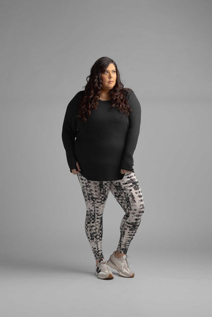 Woman wearing LuLaRoe Rise Brave leggings urban pixel weave black ivory gray abstract athletic leggings with high waist and pockets on a gray background