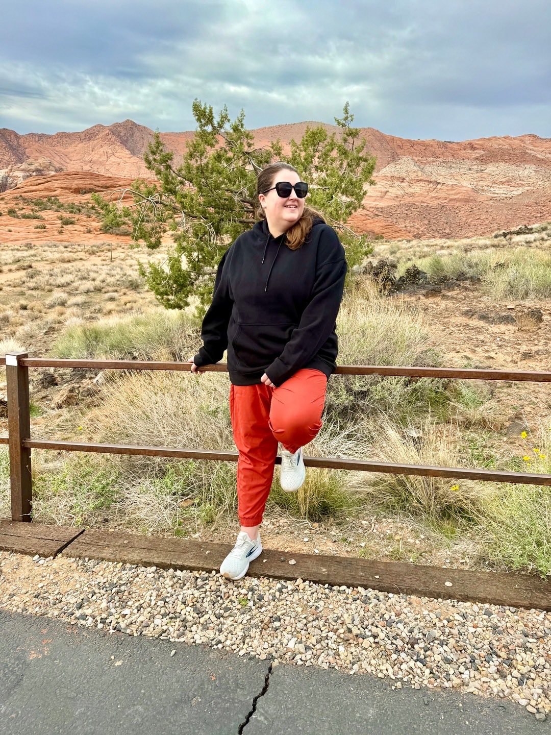 Model wearing LuLaRoe Rise Infinite Jogger in solid rust clay with elastic waistband, patch pockets, and ankle cuffs.