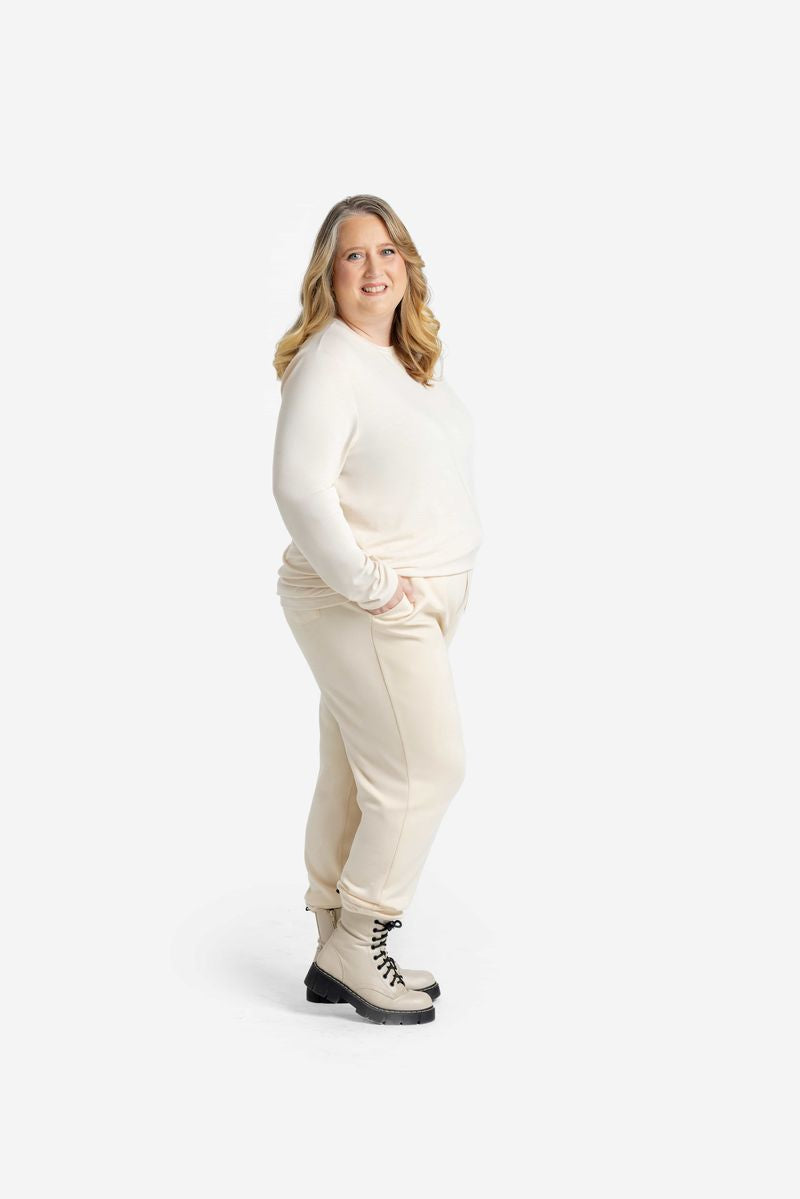 Woman wearing a cream LuLaRoe Sharon Long Sleeve Top with matching cream joggers and lace-up combat boots, posing against a white studio background.